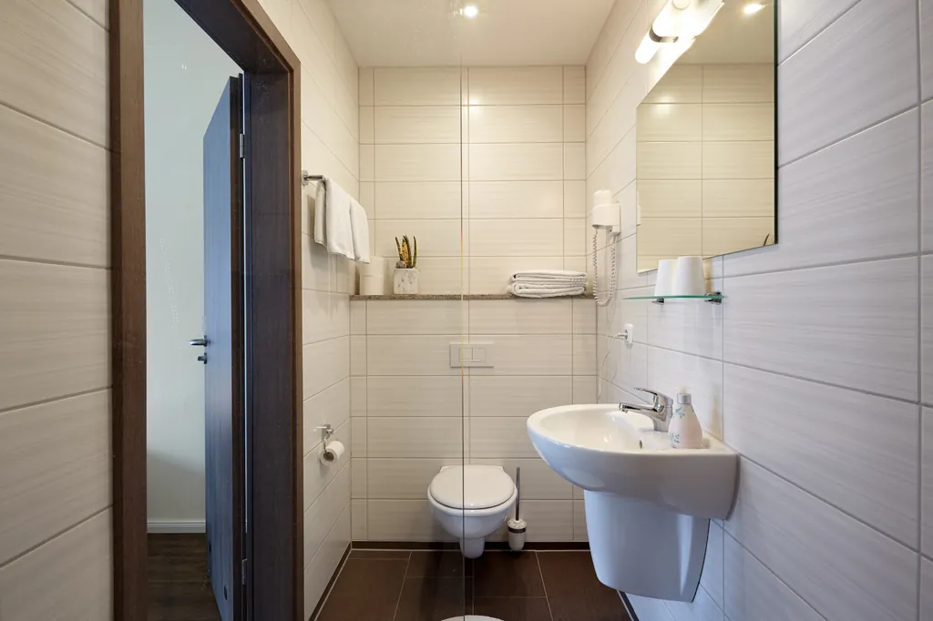 Bad mit Waschbecken, Spiegel und WC, helle Fliesen