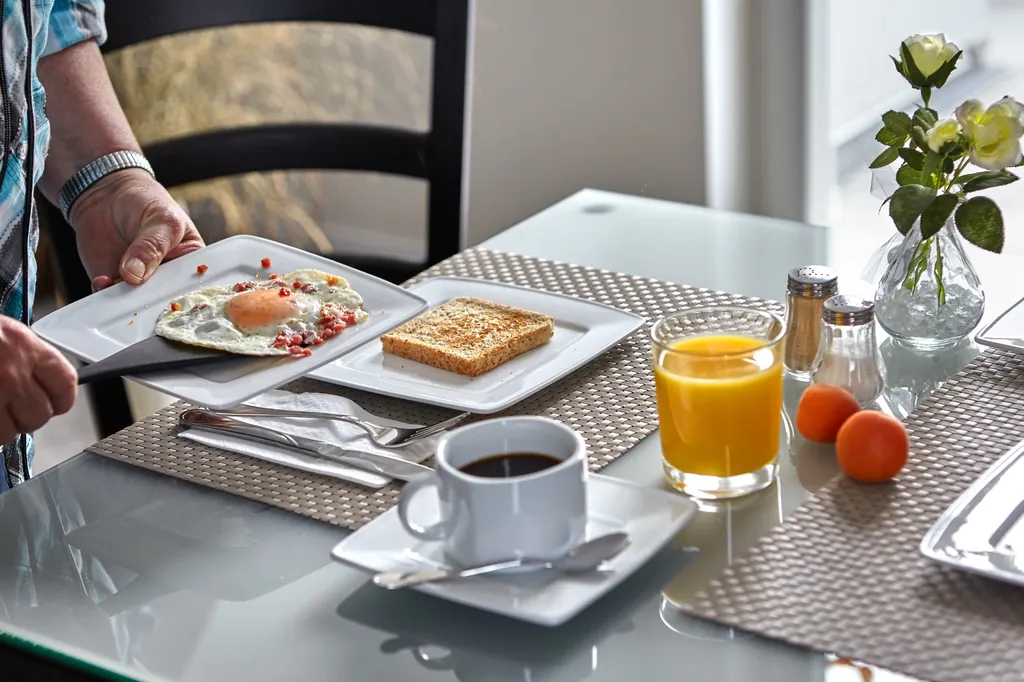 Gedeckter Frühstückstisch mit Rührei, Toast, Kaffee und Orangensaft