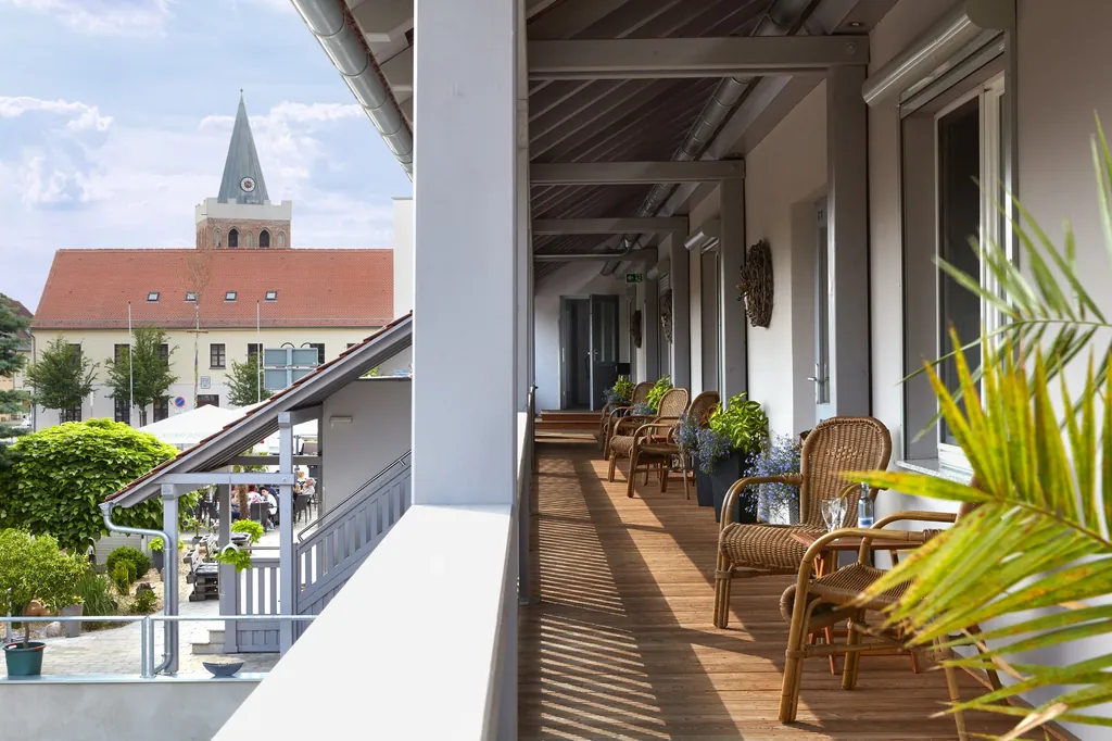 Laubengang mit Korbsesseln und Blick auf einen Kirchturm