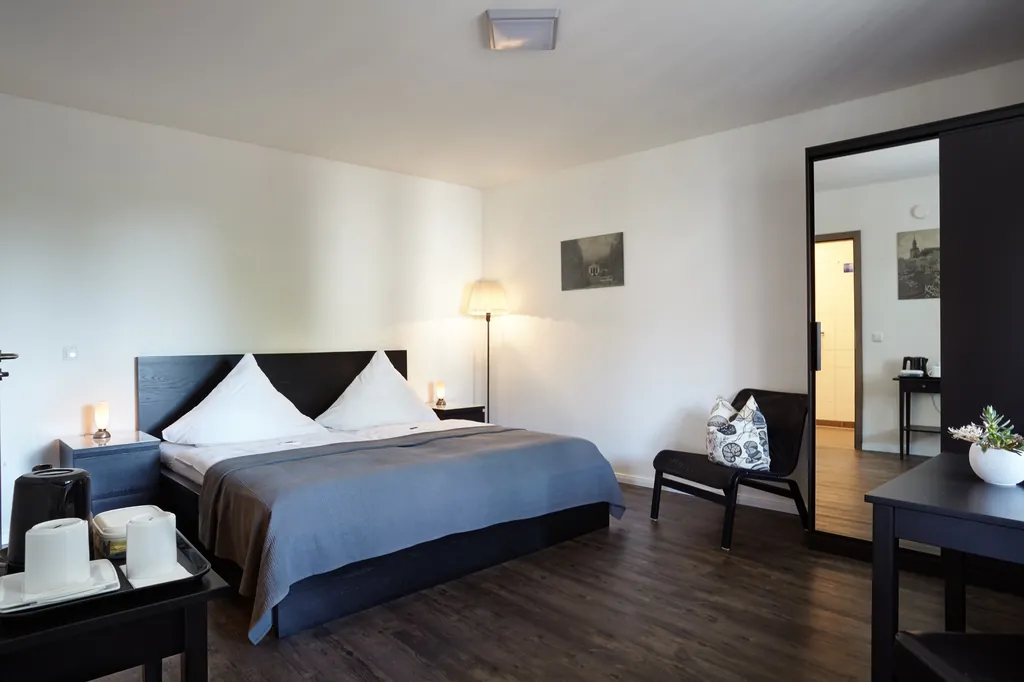 Doppelzimmer mit Doppelbett, dunklem Holzboden und Sitzecke