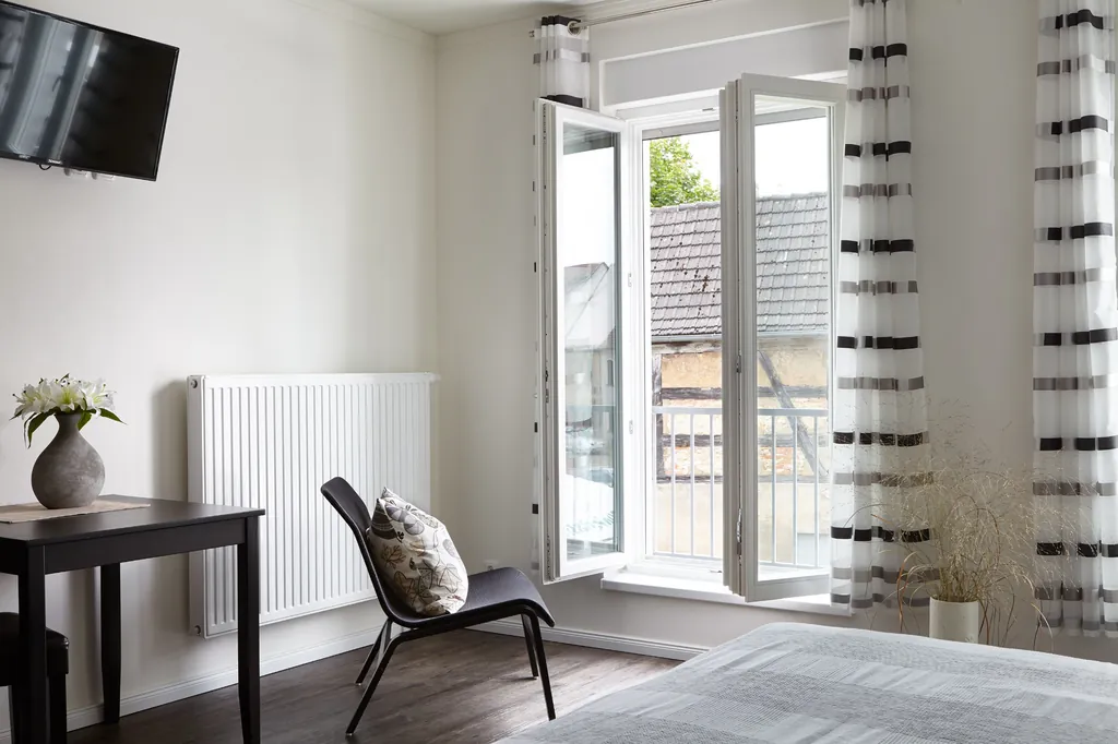 Zimmer mit bodentiefen Fenstern, Tisch, Stuhl und Fernseher